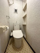 【トイレ】温水洗浄便座。壁面を利用したペーパーや掃除グッズを置ける棚があります